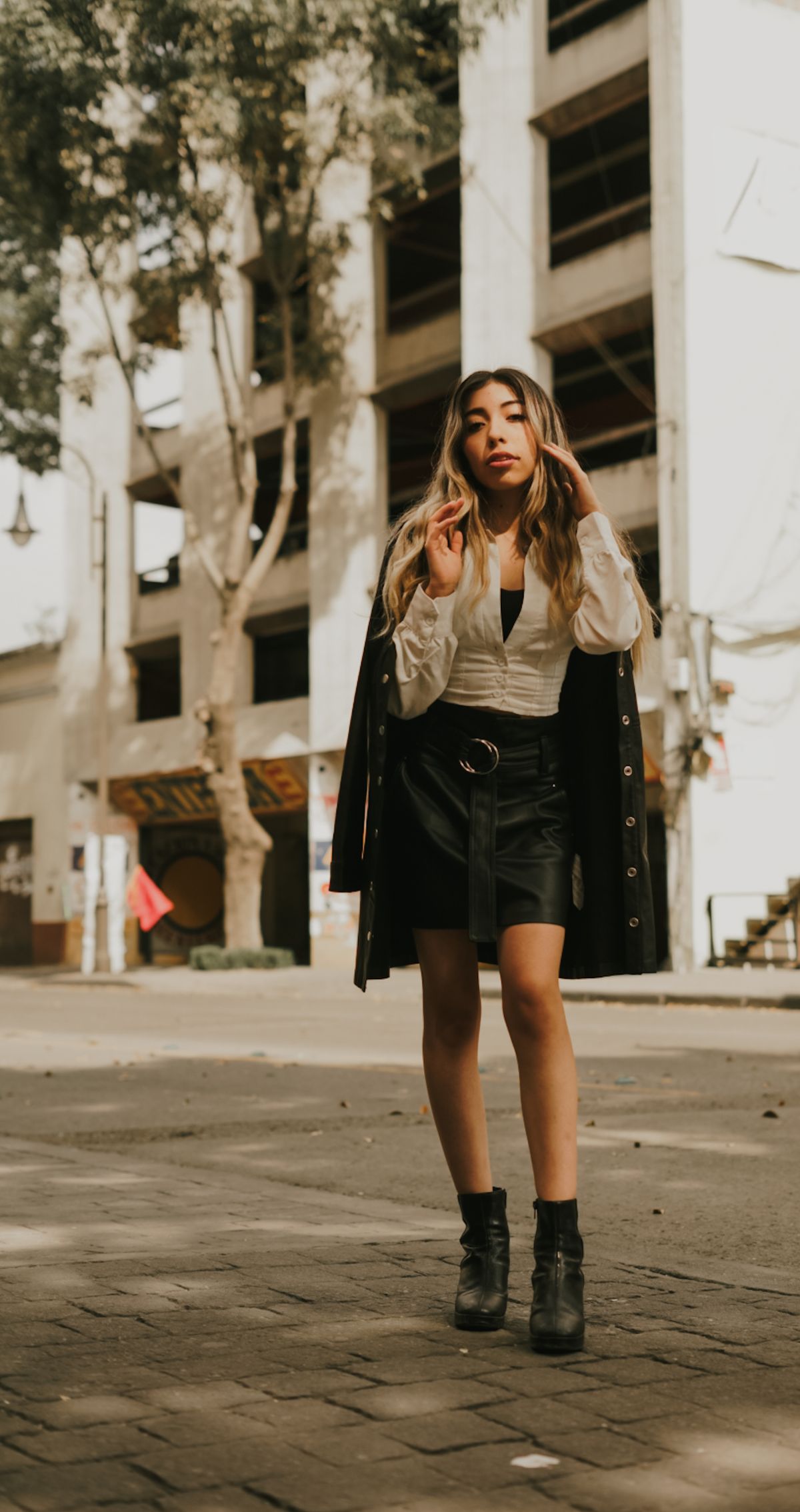 Fashionable woman wearing a coat and mini skirt outdoors in a city.